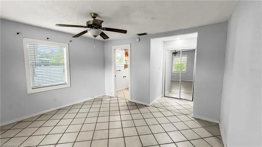 Primary bedroom featuring ceiling fan, a wealth of natural light, and a textured ceiling