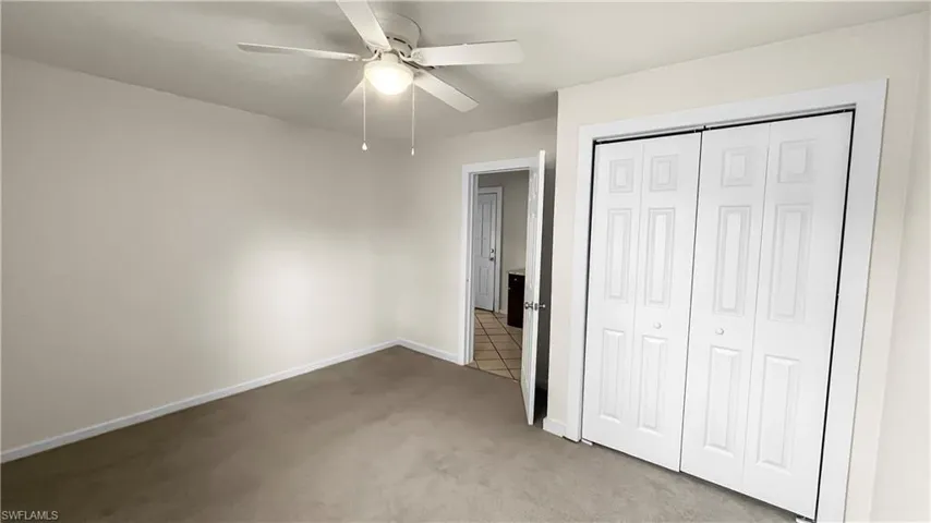 Second bedroom in main area featuring light carpet, ceiling fan, and a closet