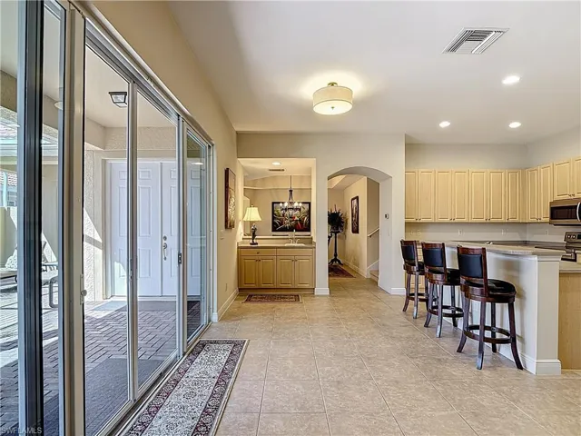 Kitchen featuring arched walkways, a kitchen bar, stainless steel appliances, recessed lighting, and light tile patterned floors