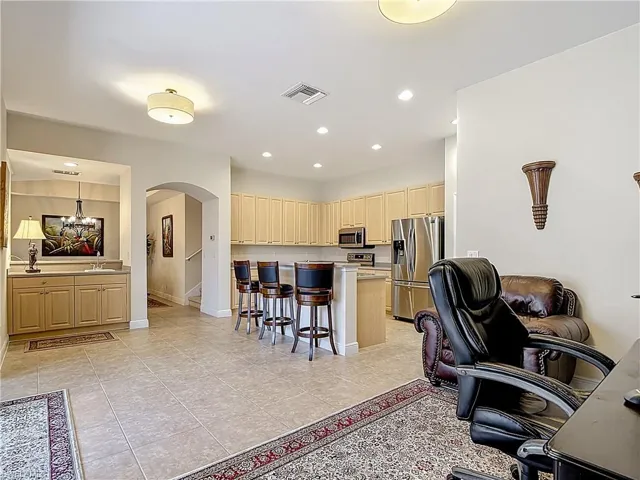 Kitchen with a breakfast bar area, stainless steel appliances, arched walkways, light countertops, and a desk / work area