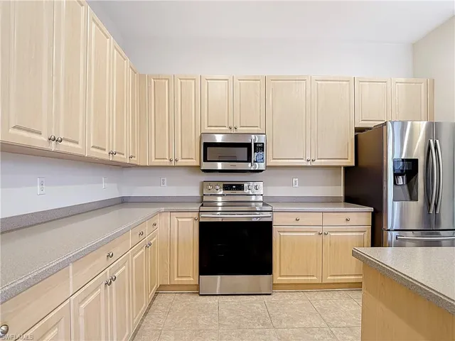 Kitchen with stainless steel appliances, light wood finish cabinetry, and light tile flooring
