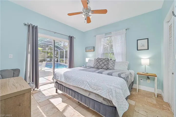 Bedroom with stone tile floors, a sunroom, access to exterior, ceiling fan, and a closet