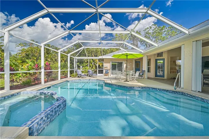 Relaxing pool / spa featuring a sunroom, a patio, and glass enclosure