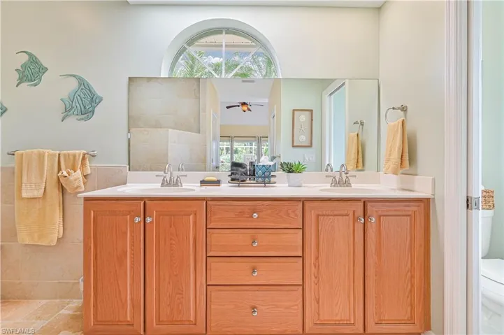 Full bath featuring double vanity, ceiling fan, and tile walls