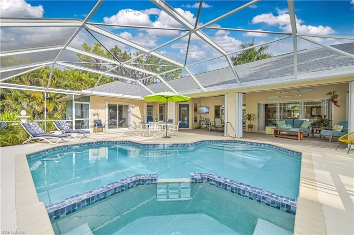 Integrated pool / hot tub featuring a sunroom, outdoor dining area, a patio, and glass enclosure