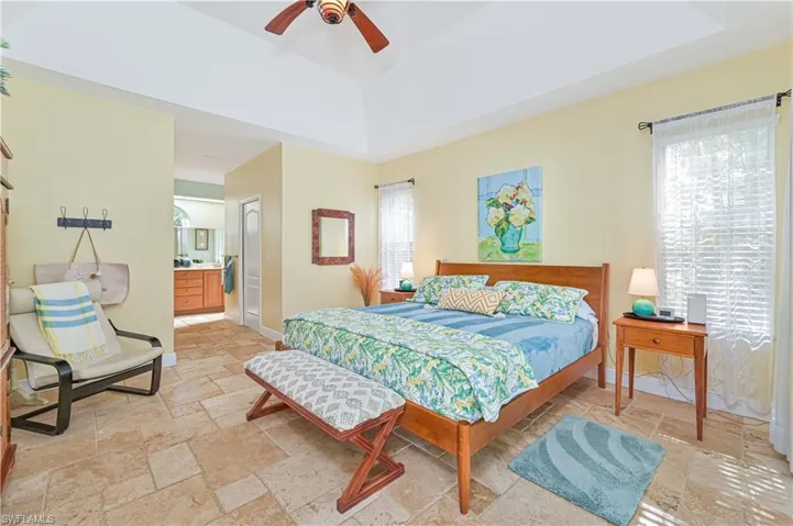 Bedroom featuring stone tile flooring, a ceiling fan, ensuite bathroom, and a closet