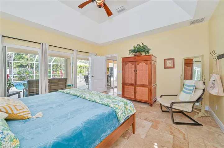 Bedroom featuring access to exterior, ceiling fan, a high ceiling, and light stone finish floors