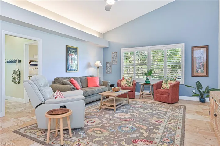 Living room with stone tile flooring, lofted ceiling, and a ceiling fan