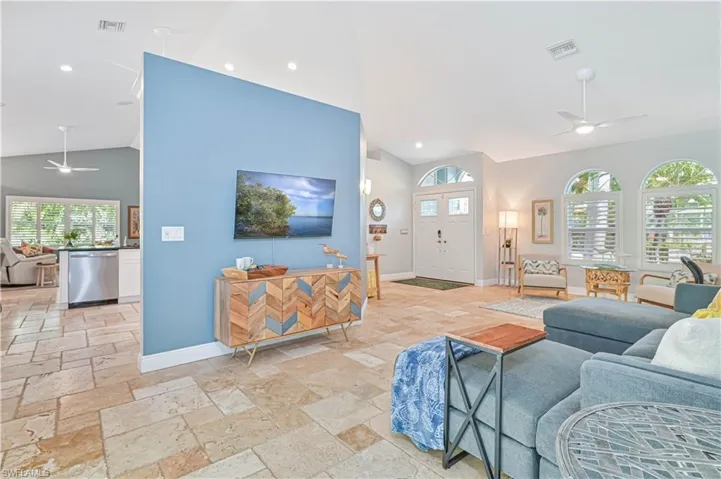 Living area with a ceiling fan, vaulted ceiling, recessed lighting, and stone tile floors