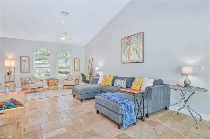 Living room with stone tile floors, vaulted ceiling, and ceiling fan