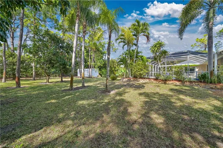 View of grassy yard featuring a sunroom, glass enclosure, and an outdoor structure