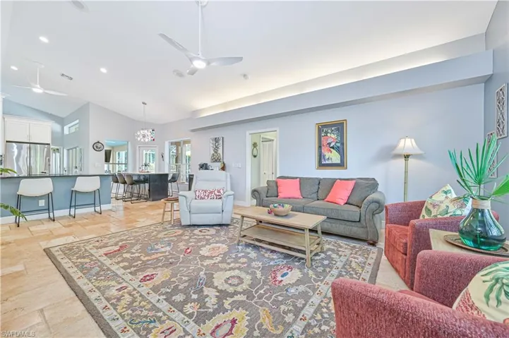 Living room with a ceiling fan, stone tile floors, vaulted ceiling, and recessed lighting