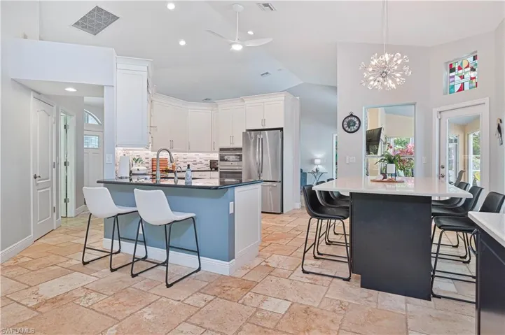 Kitchen featuring a kitchen bar, a ceiling fan, stainless steel appliances, suspended lighting, and a kitchen island