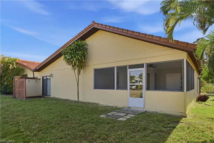 Back of house featuring stucco siding, a sunroom, and a yard