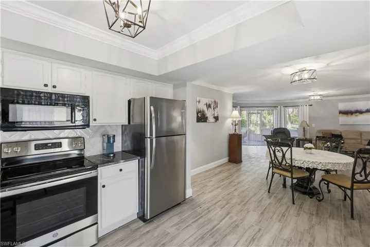 Kitchen with a chandelier, stainless steel appliances, crown molding, and white cabinetry