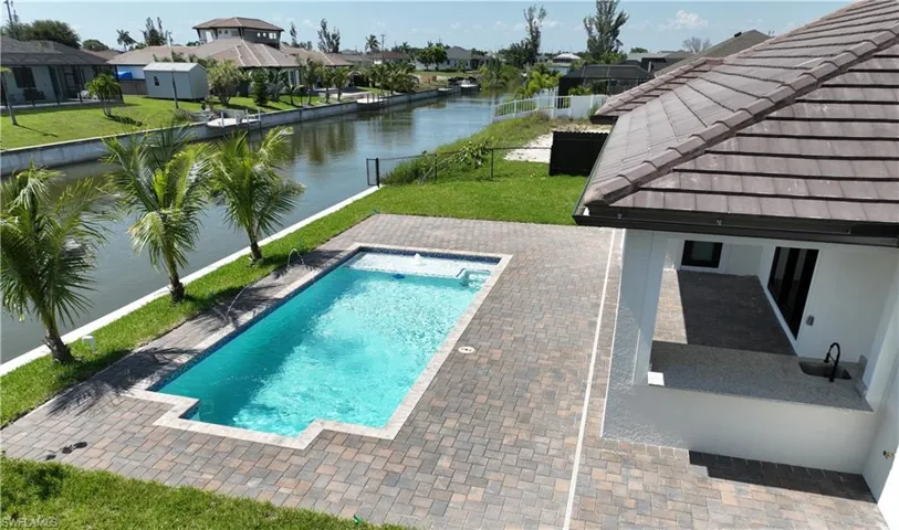 View of swimming pool with a patio area, a water view, and a yard