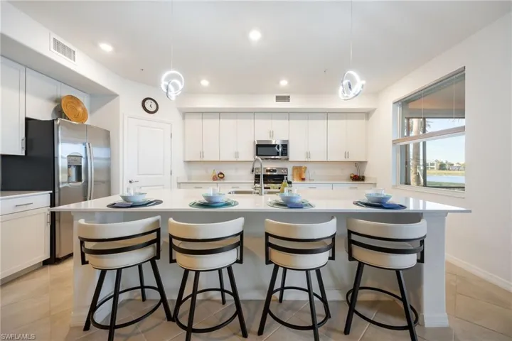 Open kitchen with white shaker style cabinets, quartz countertops & stainless steel appliances