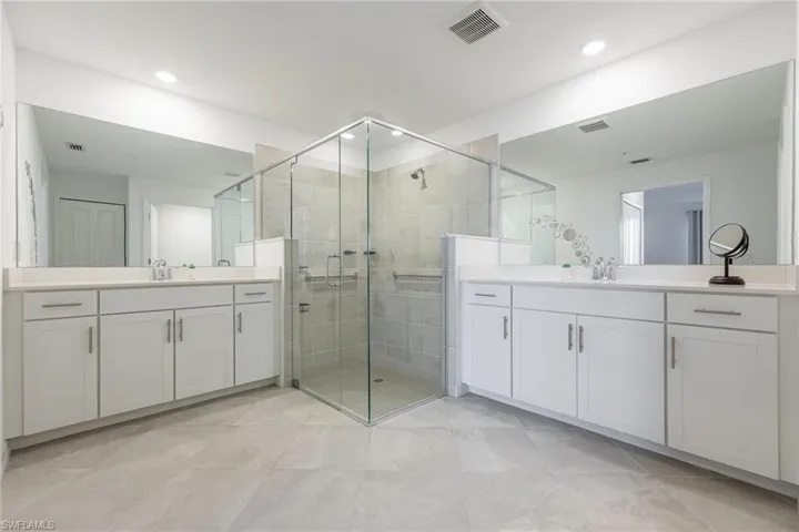 Primary Bathroom with separate vanities & a large glass shower