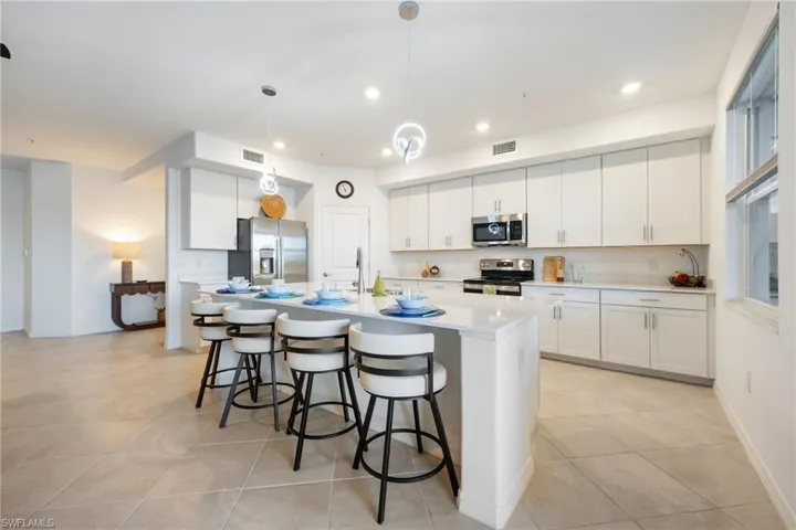 Open kitchen with white shaker style cabinets, quarts countertops & a large island