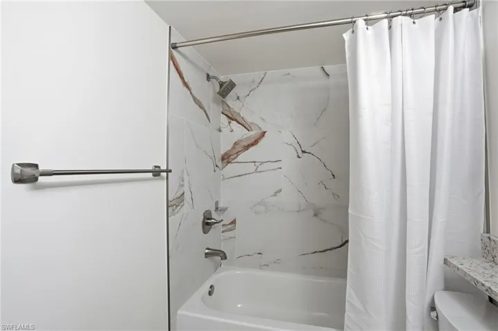 Bathroom featuring toilet and shower / tub combo with curtain - Virtually Edited Image