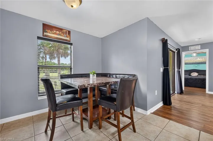 Dining area featuring tile flooring, a window with horizontal blinds, and a built-in bench seating unit