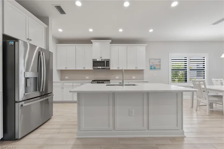 Kitchen featuring white cabinetry, an expansive center island with a stone countertop, stainless steel appliances, recessed lighting, and wood-finish tile flooring