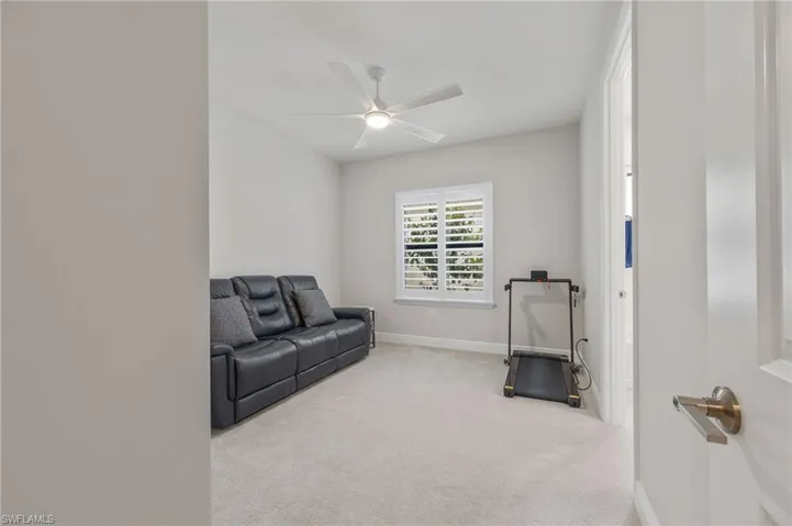 Neutral-toned room featuring neutral carpeting, a ceiling fan with integrated lighting, and a window equipped with plantation shutters