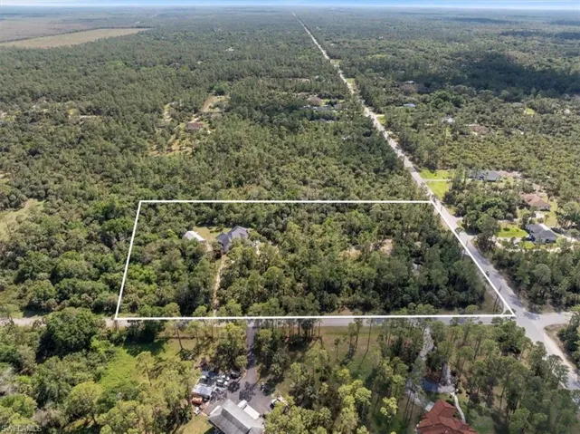 Aerial view of property and surrounding area with a heavily wooded area and property parcel outlined
