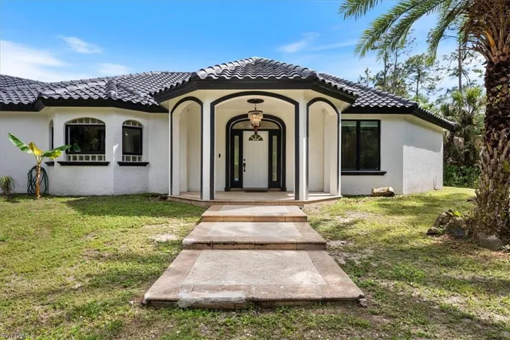 Entrance to property featuring a lawn, stucco siding, and a tile roof