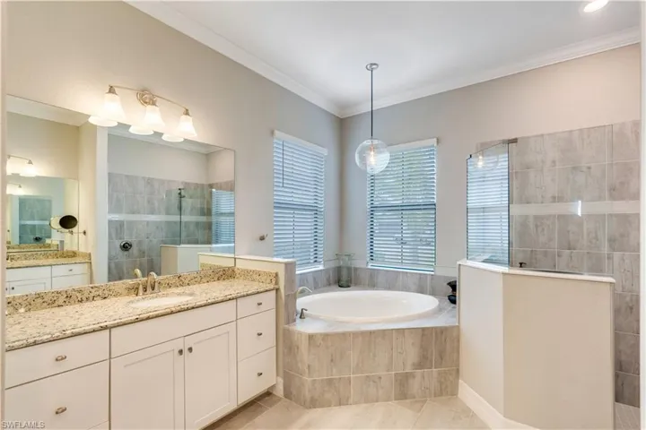Bathroom with double vanity, separate shower and tub, ornamental molding, and tile floors