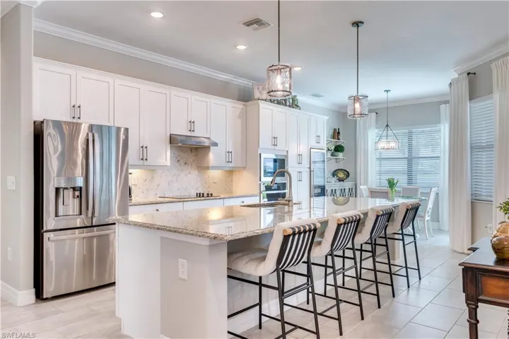 Kitchen featuring a center island with sink, appliances with stainless steel finishes, white cabinetry, and sink