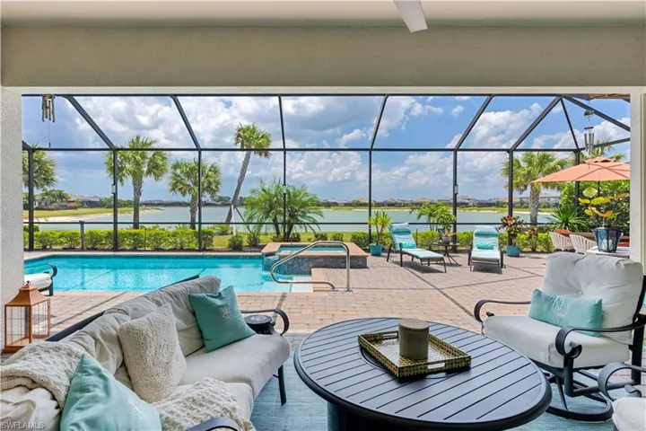 View of swimming pool featuring a patio area, a hot tub, a lanai, and a water view