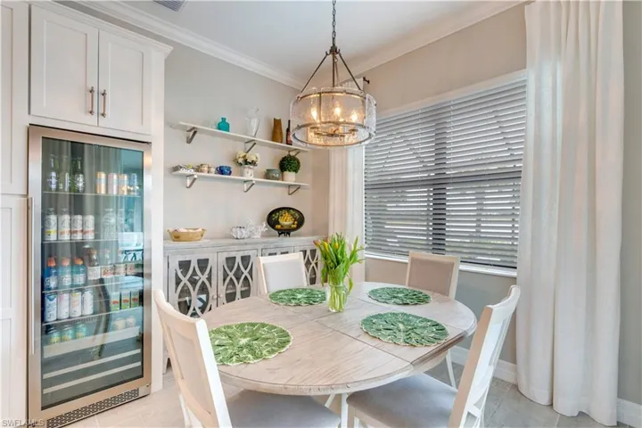 Tiled dining space featuring an inviting chandelier, ornamental molding, and beverage cooler