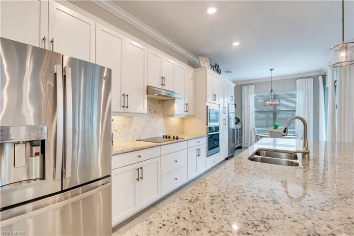 Kitchen featuring stainless steel appliances, backsplash, white cabinetry, sink, and pendant lighting