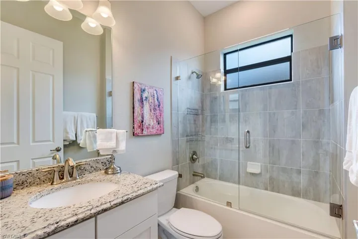Full bathroom featuring bath / shower combo with glass door, toilet, and vanity