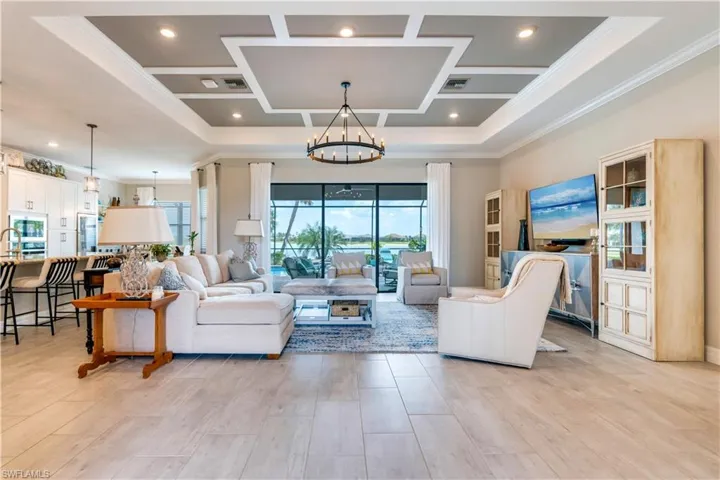 Living room with a notable chandelier, a tray ceiling, and crown molding