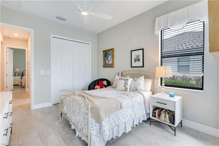 Tiled bedroom featuring ceiling fan and a closet