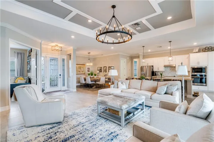 Tiled living room featuring a raised ceiling, crown molding, and a chandelier