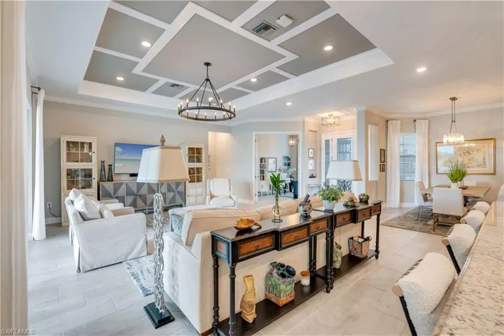 Tiled living room featuring a chandelier, ornamental molding, and a raised ceiling