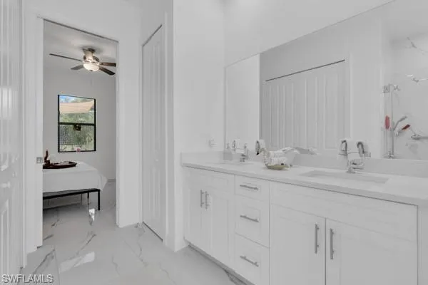 Ensuite bathroom with a closet, light marble finish floors, double vanity, a marble finish shower, and ceiling fan
