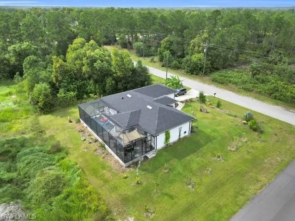 Aerial view of property and surrounding area with a forest