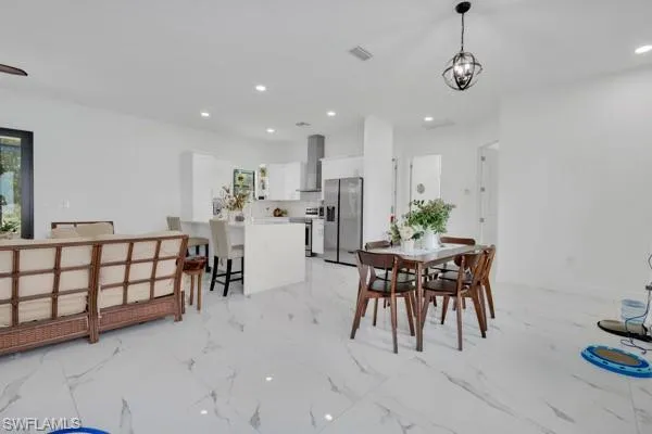 Dining room with recessed lighting and light marble finish floors