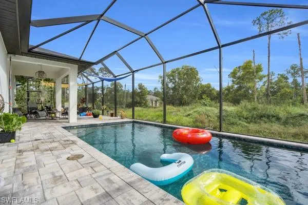 Swimming pool with a sunroom, glass enclosure, and a patio area