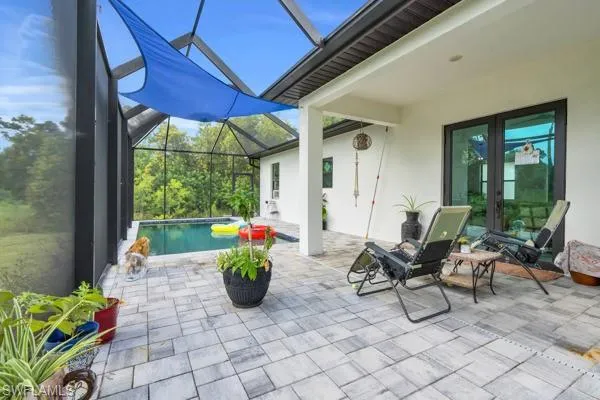 View of patio featuring a sunroom, an outdoor pool, french doors, and a lanai
