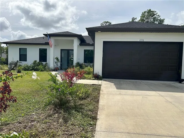 View of front of home with driveway, roof with shingles, a front yard, a garage, and stucco siding