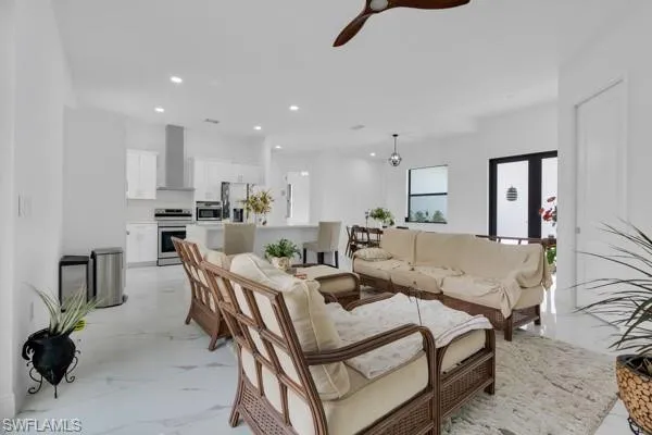 Living area with light marble finish flooring, recessed lighting, and ceiling fan