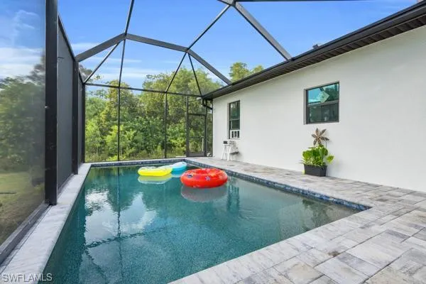 Swimming pool featuring a patio, a sunroom, and glass enclosure