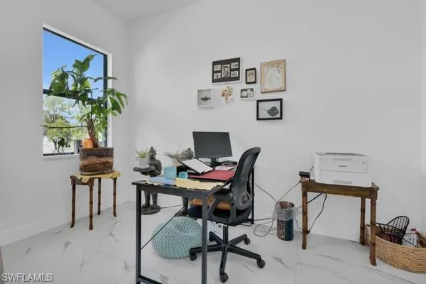 Home office featuring plenty of natural light and light marble finish flooring