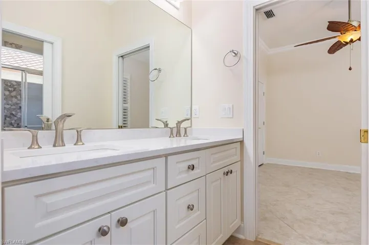 Full bath with double vanity, a ceiling fan, and ornamental molding