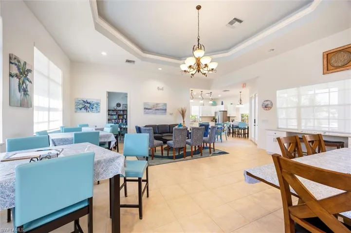 Dining area with hanging lights, light tile patterned floors, a raised ceiling, and ornamental molding